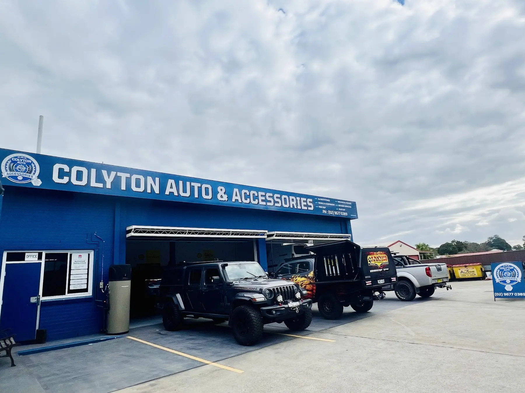 Blue Colyton Auto and Accessories workshop front with 4x4s parked outside